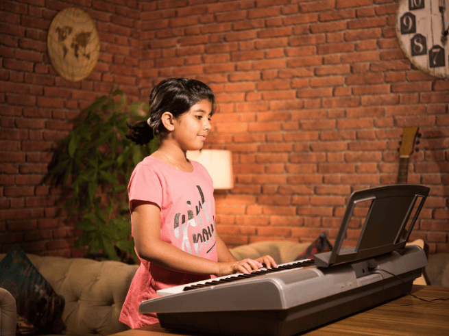 Child playing the keyboard for her online music classes for kids